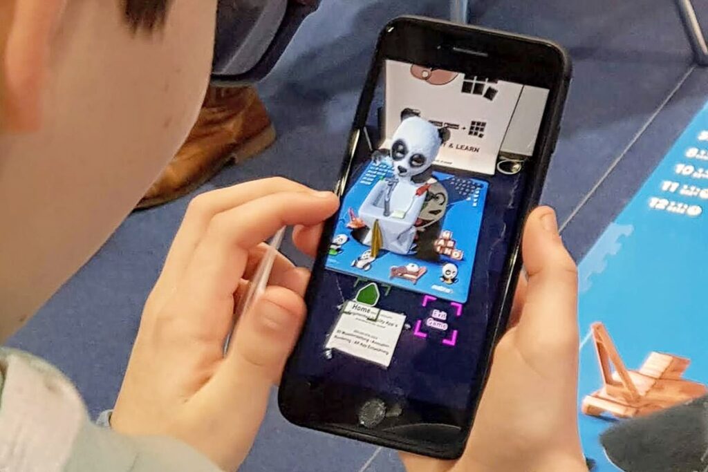 Vorschulkind hält ein Smartphone mit der AR-Projektion von BINU beim Zähneputzen in der MABINO Lern-App